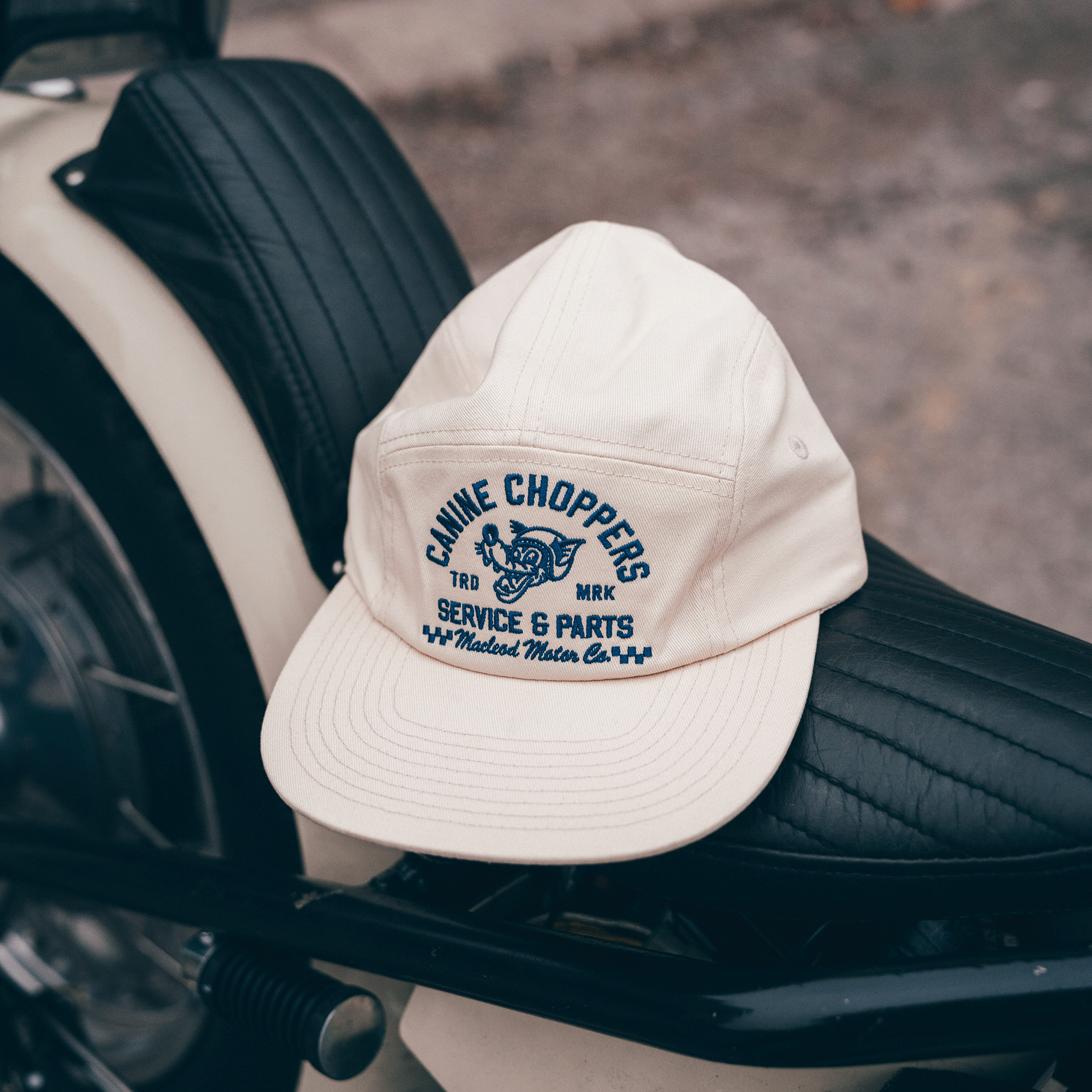 Beige cap with 'Canine Choppers' logo on a motorcycle seat