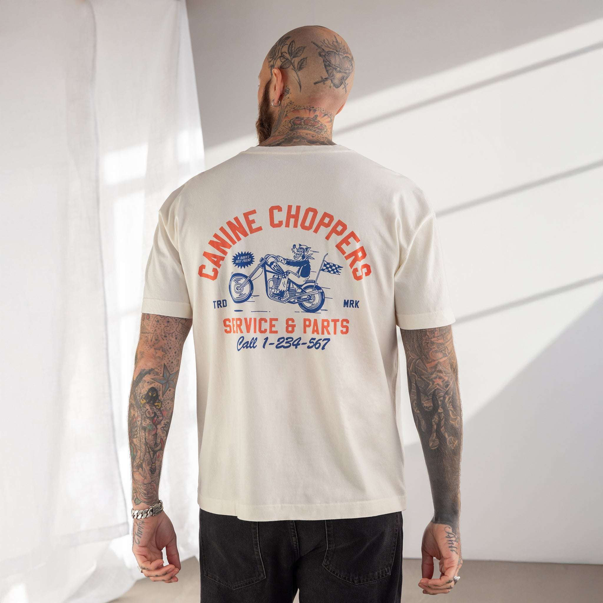 Man wearing a 'Canine Choppers' t-shirt with a motorcycle graphic on the back.