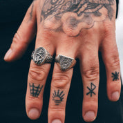 hand with tattoos and silver rings