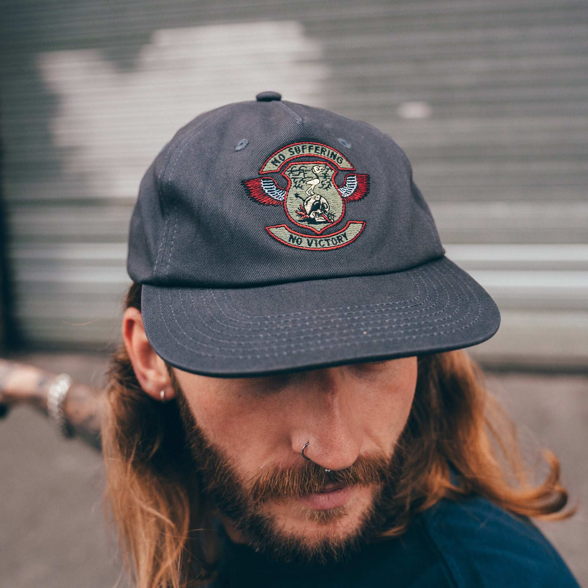 A person wearing a gray unstructured cap with a logo on the front.