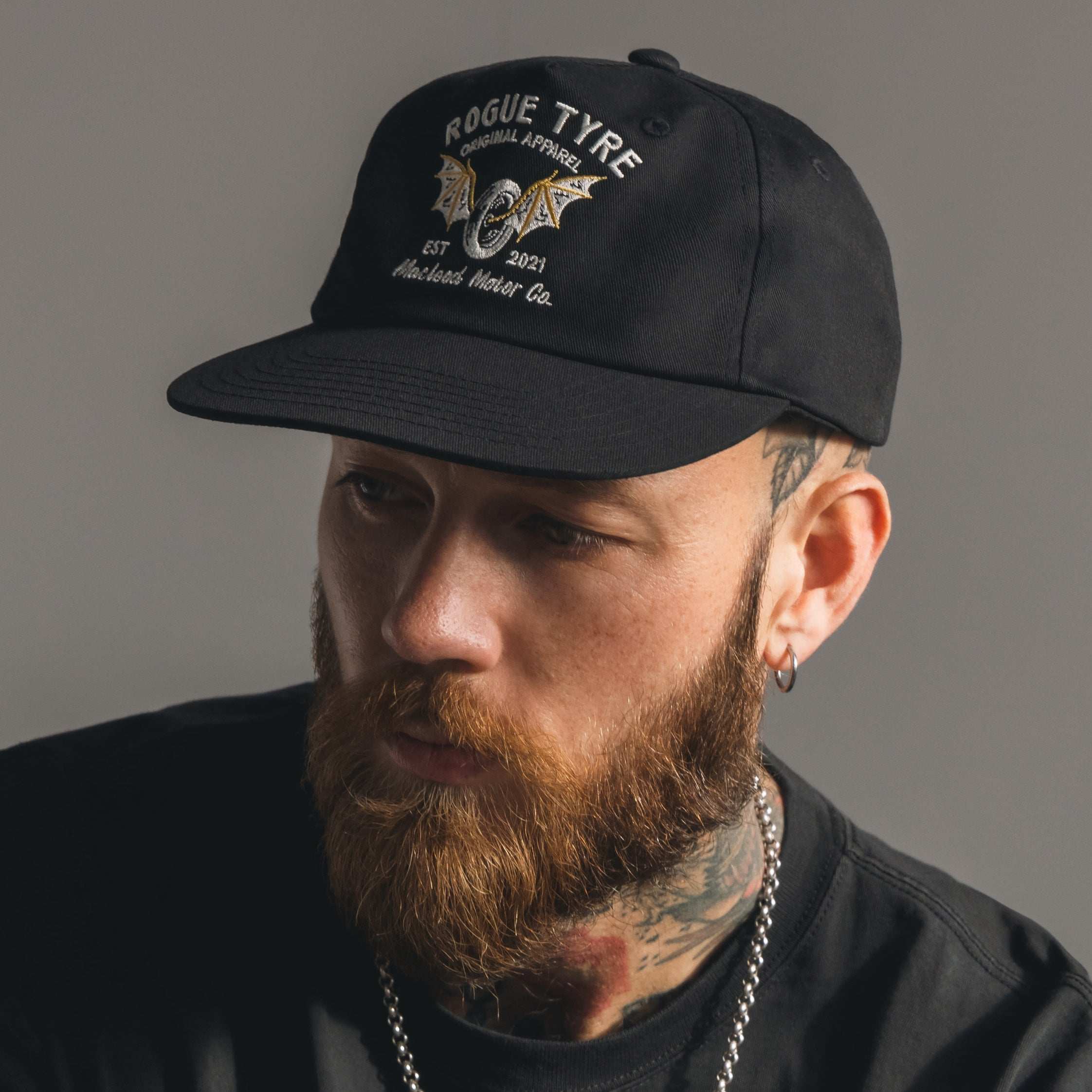 A man with a beard and mustache wearing a black unstructured cap with the 'ROGUE TYRE' logo on the front.