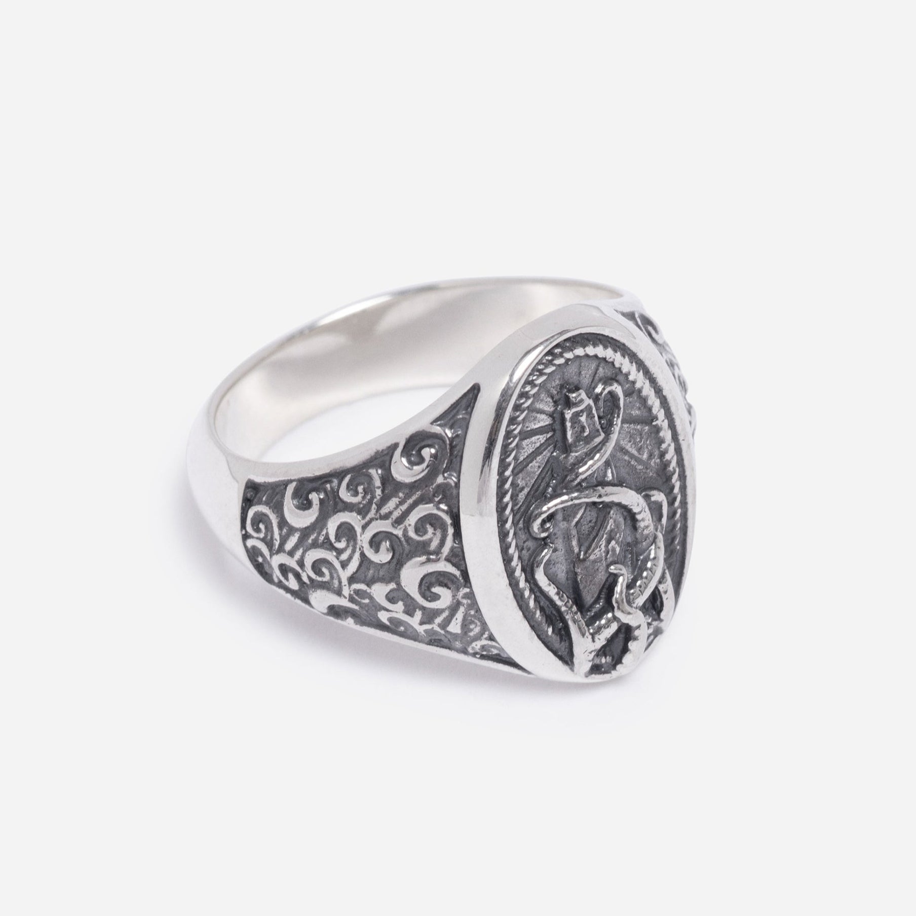 Silver ring with intricate designs on a light gray background