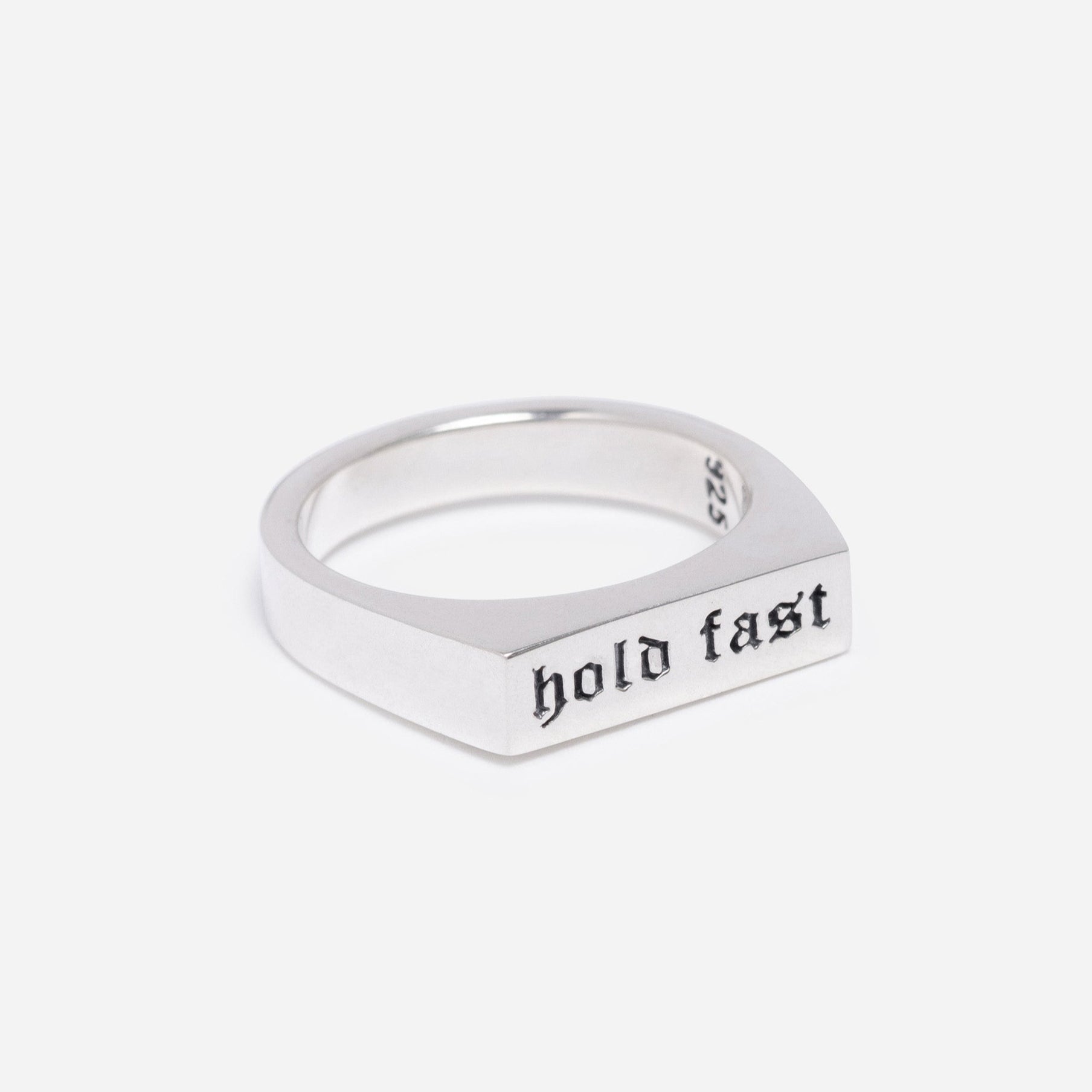 Silver ring with 'hold fast' engraving on a light gray background