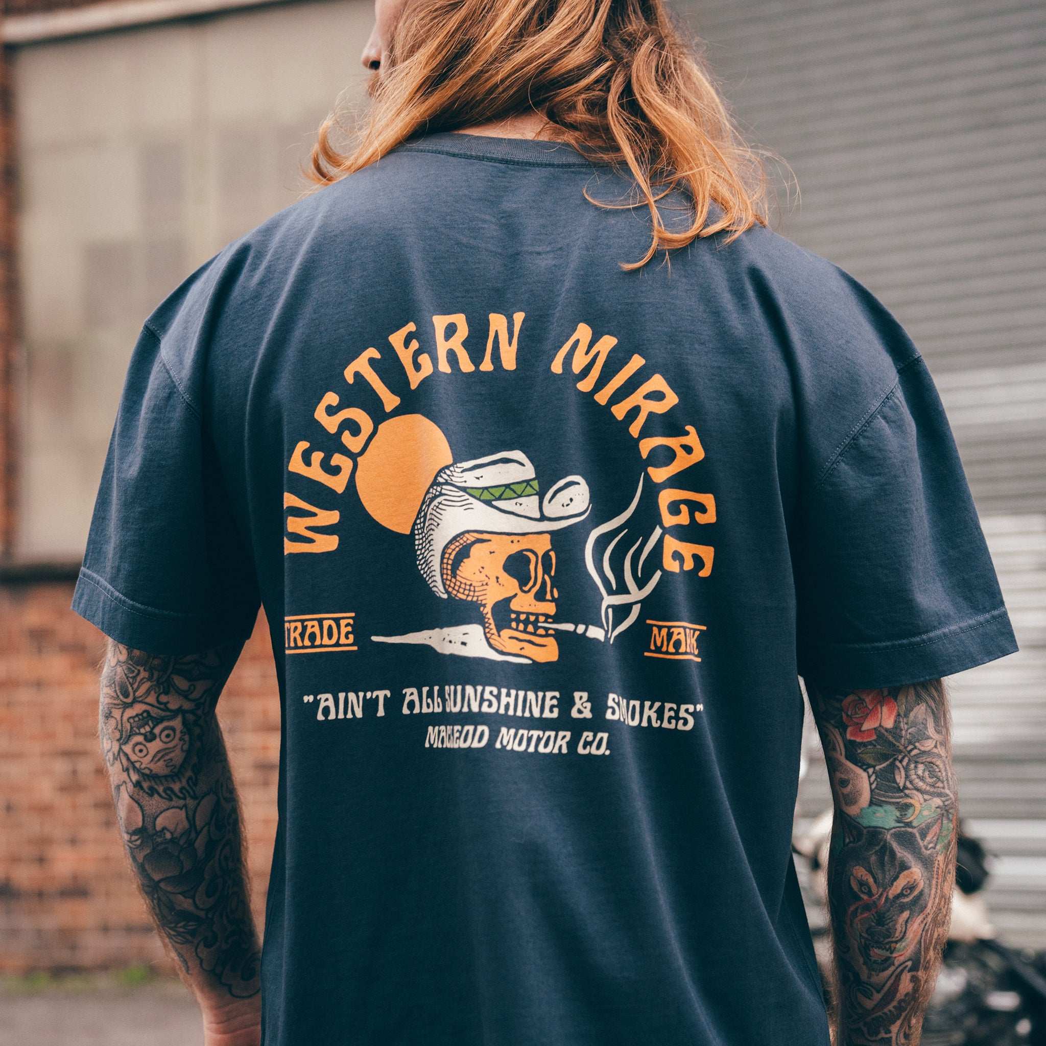 Person wearing a navy blue t-shirt with 'Western Mirage' graphic design on the back.